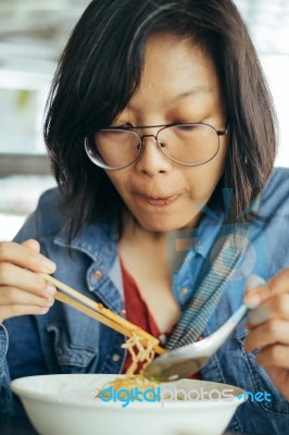 Women Eating Egg Noodle With Crispy Pork From Chopsticks And Met… Stock Photo