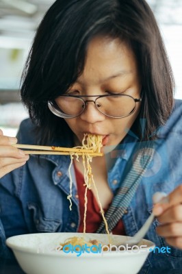 Women Eating Egg Noodle With Crispy Pork From Chopsticks And Met… Stock Photo