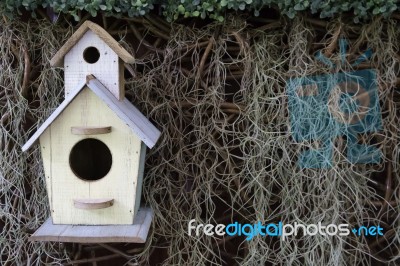 Wood Bird House On Dry Grass And Green Leaf Background Stock Photo