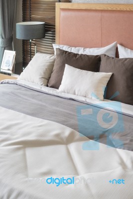 Wooden Bed With White And Brown Pillows In Bedroom Stock Photo