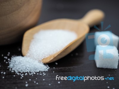 Wooden Bowl And Spoon With Sugar Cube On Dark Wood Background Stock Photo