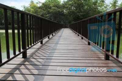 Wooden Bridge Over The Lake Through The Forest Stock Photo