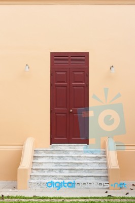 Wooden Brown Door On Orange Wall Stock Photo