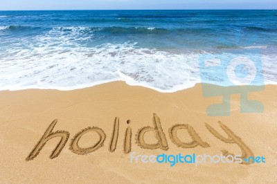 Word Holiday Written In Sand On Beach Stock Photo