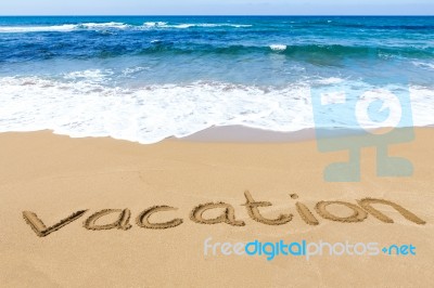 Word Vacation Written In Sand Of Beach At Sea Stock Photo