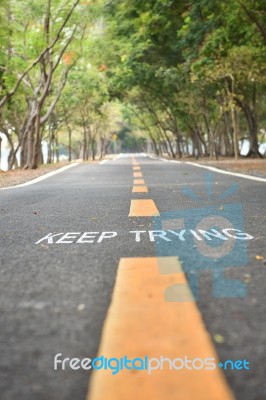 Words Of Keep Trying With Yellow Line Marking On Road Surface In The Park Stock Photo