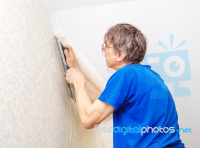 Worker In Protective Gloves With Spatula Smoothing Wallpaper Stock Photo