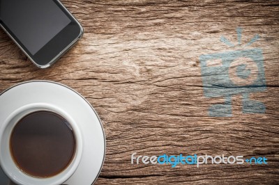 Working Space. Focused On A Cup Of Coffee And Smartphone On Old Wooden Background. Working In The Morning Concept Stock Photo