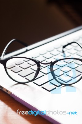 Workspace With Eyeglasses On Laptop Stock Photo