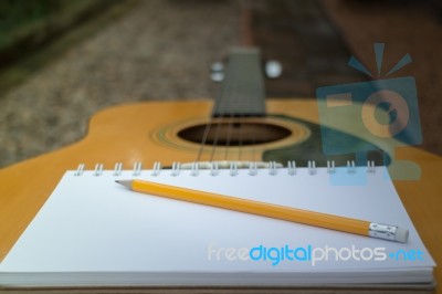 Yellow Acoustic Guitar On Wooden Table Stock Photo