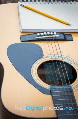 Yellow Acoustic Guitar On Wooden Table Stock Photo