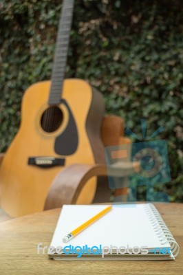 Yellow Acoustic Guitar On Wooden Table Stock Photo