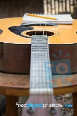 Yellow Acoustic Guitar On Wooden Table Stock Photo