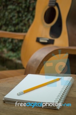 Yellow Acoustic Guitar On Wooden Table Stock Photo