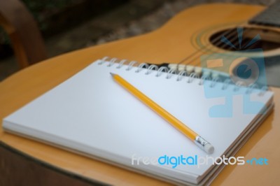 Yellow Acoustic Guitar On Wooden Table Stock Photo