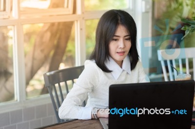 Young Asian Woman Working With Laptop In Coffee Shop Stock Photo