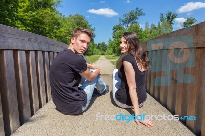 Young Attractive Dutch Couple Sitting On Wooden Bridge Stock Photo