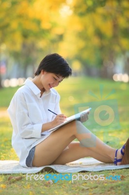 Young Beautiful Asian Woman Writing Text In Diary Book In Yellow… Stock Photo