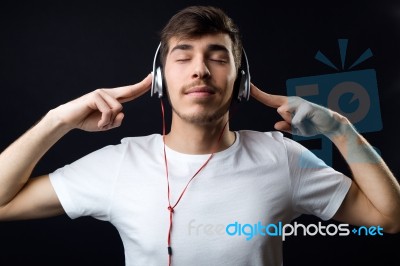 Young Beautiful Man Listening To Music. Isolated On Black Stock Photo