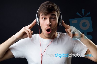 Young Beautiful Man Listening To Music. Isolated On Black Stock Photo