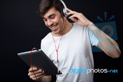 Young Beautiful Man Listening To Music. Isolated On Black Stock Photo