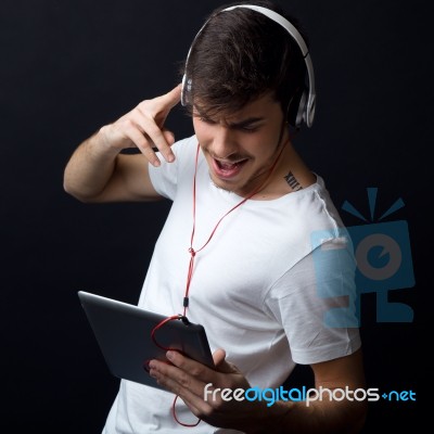 Young Beautiful Man Listening To Music. Isolated On Black Stock Photo