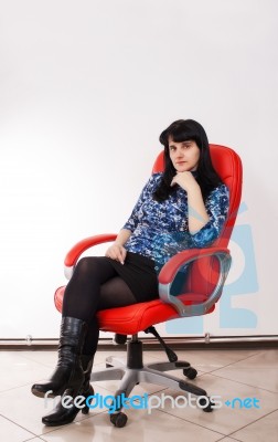 Young Beautiful Woman Posing Sitting On A Red Chair Stock Photo