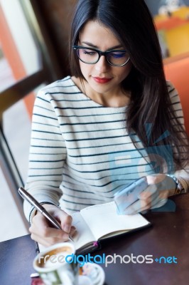 Young Beautiful Woman Using Her Mobile Phone In Coffee Stock Photo