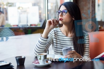 Young Beautiful Woman Using Her Mobile Phone In Coffee Stock Photo