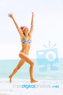 Young Blonde Woman In Bikini And Christmas Santa Hat Jumping On Stock Photo