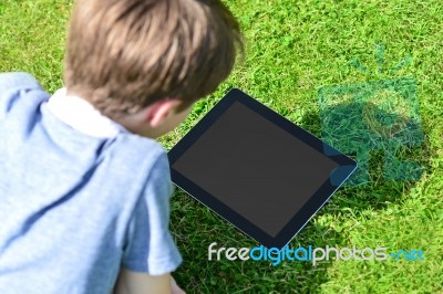 Young Boy Using Digital Tablet Outdoors Stock Photo