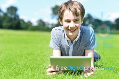 Young Boy With Tablet Device At Grassland Stock Photo