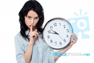 Young Brunette With Wall Clock Gesturing Silence Stock Photo