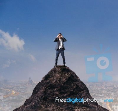 Young Business Man Standing On Top Of Mountain And Spying By Bin… Stock Photo