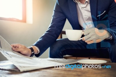 Young Businessman Sitting In A Cafe Drinking Coffee And Reading Stock Photo