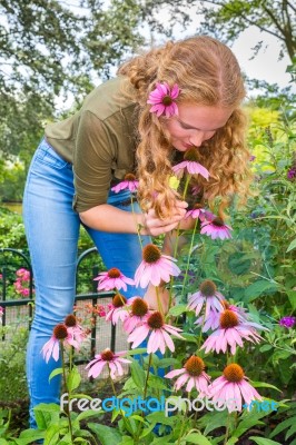 Young Caucasian Woman Smelling Echinacea Flower In Garden Stock Photo