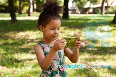 Young Child Using Smartphone At Park Stock Photo