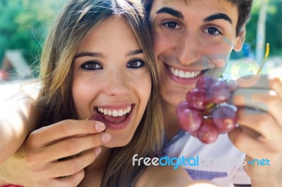 Young Couple Eating Grapes On Romantic Picnic In Countryside Stock Photo