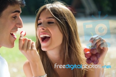 Young Couple Eating Grapes On Romantic Picnic In Countryside Stock Photo