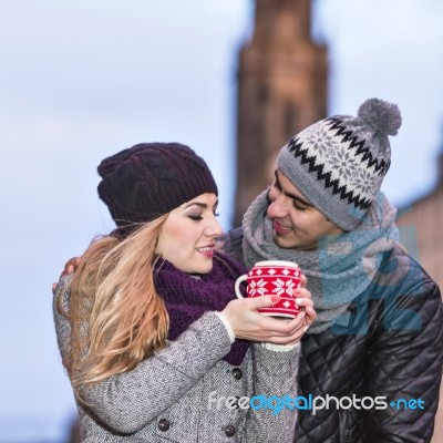 Young Couple In Love Embracing And Drinking Hot Drink From Red C… Stock Photo