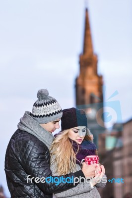 Young Couple In Love Embracing And Drinking Hot Drink From Red C… Stock Photo