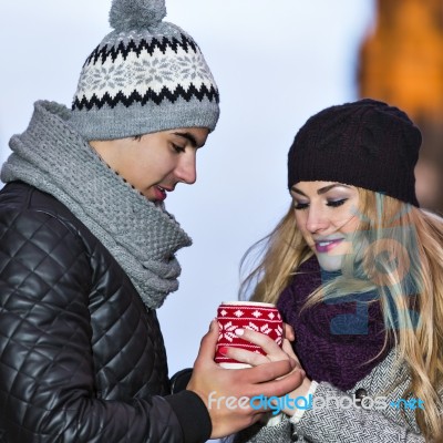 Young Couple In Love Embracing And Drinking Hot Drink From Red C… Stock Photo