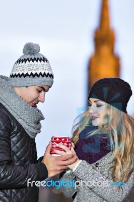 Young Couple In Love Embracing And Drinking Hot Drink From Red C… Stock Photo