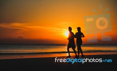 Young Couple: Man And Woman Run Together On A Sunset On Lake Coa… Stock Photo