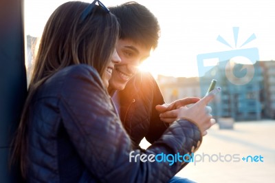 Young Couple Of Tourist In Town Using Mobile Phone Stock Photo