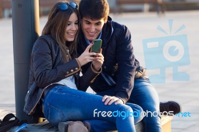 Young Couple Of Tourist In Town Using Mobile Phone Stock Photo
