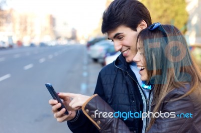 Young Couple Of Tourist In Town Using Mobile Phone Stock Photo