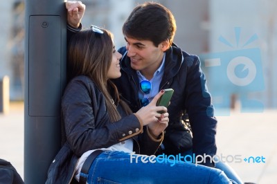 Young Couple Of Tourist In Town Using Mobile Phone Stock Photo