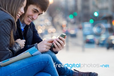 Young Couple Of Tourist In Town Using Mobile Phone Stock Photo