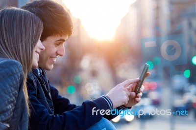 Young Couple Of Tourist In Town Using Mobile Phone Stock Photo